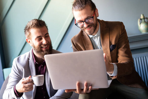 Sharing fresh ideas. Group of young business people in smart casual wear talking and smiling while standing in the office