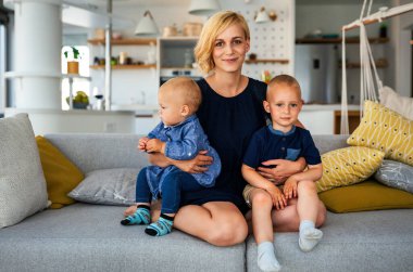 Mutlu bir şekilde gülümseyen, çocuklarını kucaklayan güzel bir annenin portresi. Aile, aşk, çocuk konsepti.