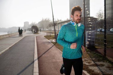 Genç yakışıklı fitness adamı şehir bölgesinde koşuyor.