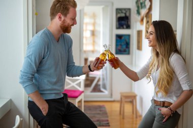 Birbirini seven mutlu çift evde bira içip kadeh kaldırıyor.