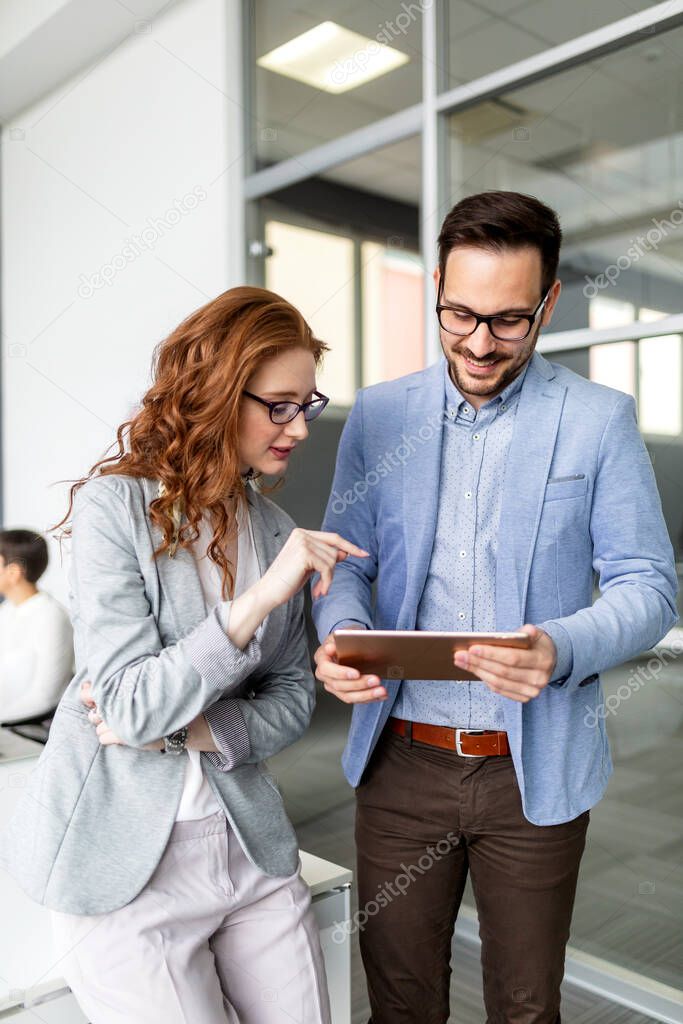 Happy business partners discussing documents and ideas at meeting in office