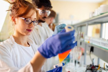 Laboratuvarda çalışan bir grup genç öğrenci ve bilim adamları.