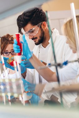 Laboratuvarda çalışan genç öğrenciler ve kimya bilimcileri.