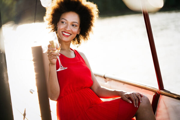 Lifestyle fashion portrait of stunning black woman resting outdoor. Glass in hand. Drinking champagne.