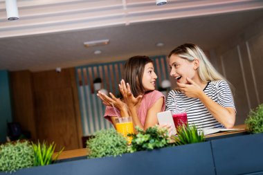 Mutlu genç bayan arkadaşlar eğleniyor, konuşuyor ve gülümsüyor.