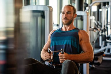 Spor salonunda antrenman yaparken genç, formda kaslı bir adam.