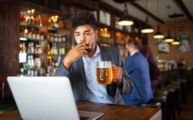 İnsanlar, nikotin bağımlılığı ve kötü alışkanlıklar konsepti. Bir adamın bira içip, barda sigara içmesine yakın.