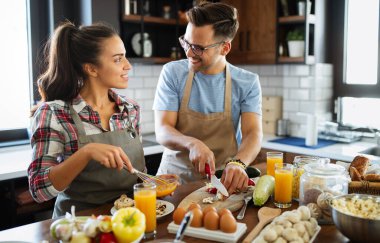 Güzel genç bir çift mutfakta birlikte yemek pişirirken eğleniyor.
