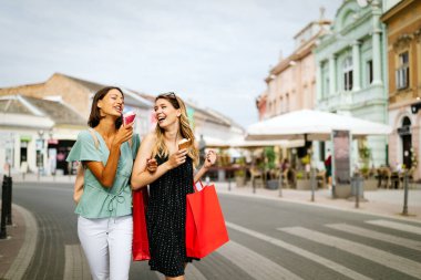 Alışveriş, satış, mutlu insanlar ve turizm konsepti. Sırıtkan kadın arkadaşlar alışveriş torbaları ile