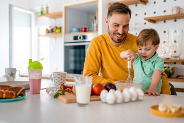 Mutlu aile evi mutfak konsepti. Çocuklarla gülümseyen baba sağlıklı yemekler hazırlıyor ve birlikte vakit geçiriyorlar.