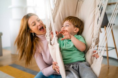 Aile, çocukluk, bekar ebeveyn ve insan konsepti. Mutlu anne ve küçük oğlu evde oynayıp eğleniyor.