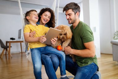 Mutlu genç aile eğleniyor, evde köpeklerle oynuyorlar.