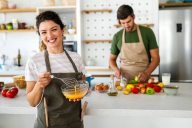 Mutlu genç çift mutfakta eğlenirken taze organik yiyecekler hazırlıyor.