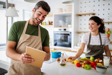 Mutlu genç çift, taze sebze hazırlarken modern mutfakta eğleniyor.