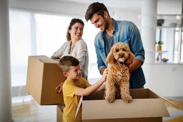 Husband and wife and their son with dog moving in new home. Family, relocation, moving in concept.