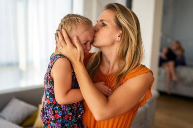 Genç anne ağlayan küçük kızını teselli ediyor. Ebeveynlik, aile destek kavramı