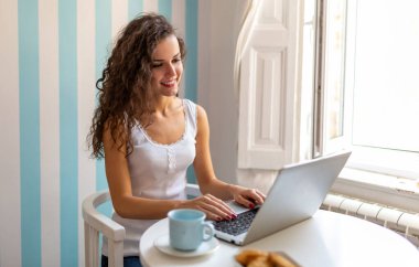 Evde dizüstü bilgisayarı olan genç, şehvetli bir kadın.