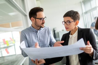 Mutlu iş ortakları ofiste belgeleri ve fikirleri tartışıyor.