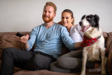 Mutlu genç çift oynuyor, evde köpekle rahatlıyor.