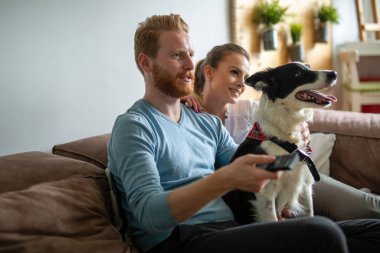 Mutlu genç çift oynuyor, evde köpekle rahatlıyor.