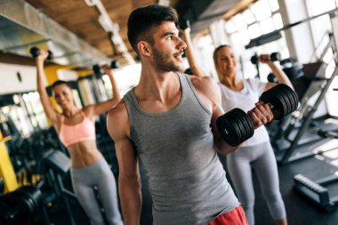 Sağlıklı kalmak için spor salonunda egzersiz yapan sağlıklı bir grup genç. Spor, dostum, egzersiz konsepti