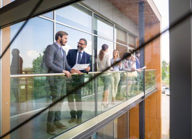 Başarılı, mutlu iş adamları ofis dışında kahve molası sırasında konuşuyor ve gülümsüyor.