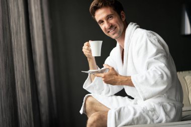 Bornozlu bir erkek çay ve kahve içerken dinleniyor.