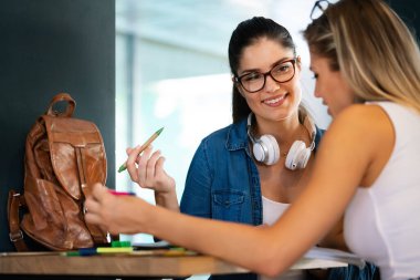 Mutlu üniversite öğrencileri üniversitede kitaplarla okuyorlar.