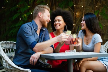 Çeşitli mutlu arkadaşlar yaz aylarında kafede eğleniyor, konuşuyor, gülümsüyor.