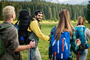 Bir grup sağlıklı arkadaş dağlarda yürüyüş yapıyor.