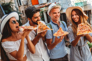 Arkadaşlar dışarıda eğleniyor, yaz tatilinde pizza yiyorlar.