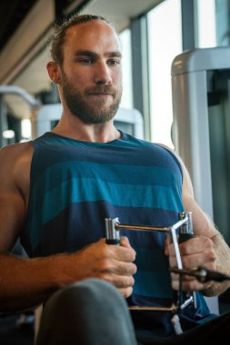 Spor salonunda antrenman yaparken genç, formda kaslı bir adam.