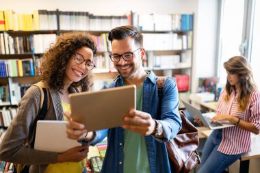 Bir grup öğrenci arkadaş kütüphanede çalışıyor. Üniversite sınavına hazırlanma ve öğrenme.