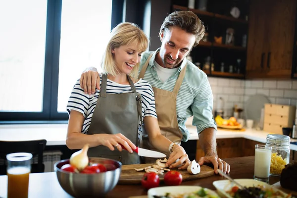 Birlikte yemek pişiren mutlu çift. Erkek ve kadın mutfaklarında sağlıklı yiyecekler hazırlıyorlar.