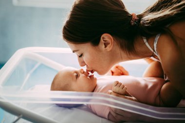 Güzel, sevgi dolu bir annenin portresi ilk maçlarını yatak odasında bebeğiyle oynuyor.