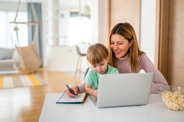 Annesi laptopunda oğluyla birlikte evde çalışıyor.