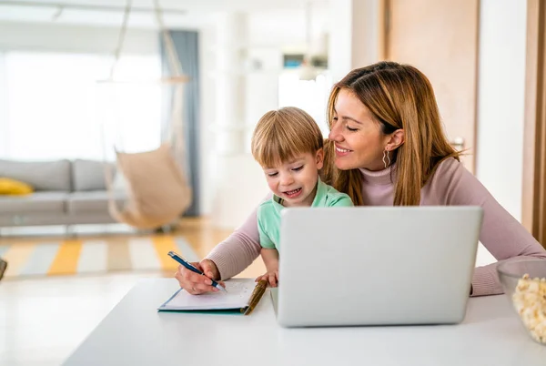 Mother working at home-office with son on her laptop
