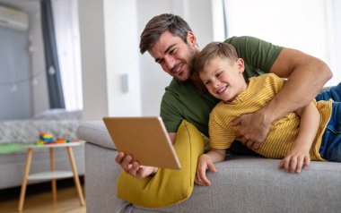 Mutlu baba ve oğul evde dijital tabletle oynuyor. Mutlu aile, teknoloji, eğlence konsepti