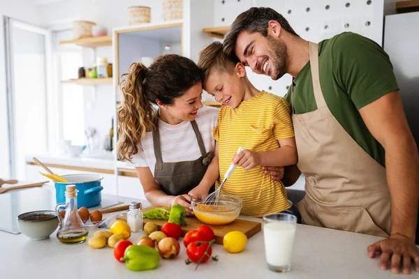 Happy young family preparing healthy food together in kitchen