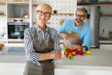 Mutlu son sınıf çifti mutfakta birlikte yemek pişiriyor.