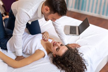 Genç çift dizüstü bilgisayarlarıyla evde dinleniyor. Aşk, mutluluk, insanlar ve eğlence konsepti.