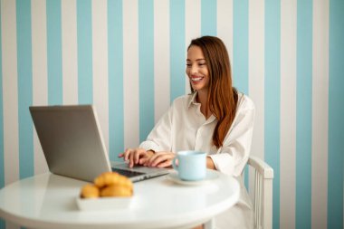 Evde dizüstü bilgisayarı olan genç, şehvetli bir kadın.