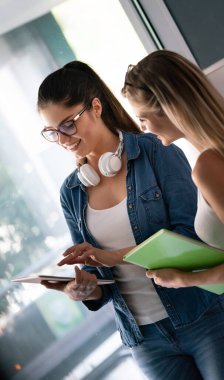 Mutlu üniversite öğrencileri üniversitede kitaplarla okuyorlar.