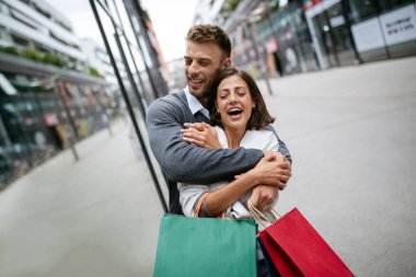 Alışveriş ve eğlence zamanı. Mutlu, başarılı, mutlu, alışveriş torbaları ve kahkahalarla dolu genç bir çift.