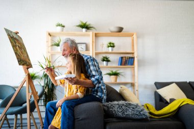 Aile, nesil, ilişkiler ve insan kavramı. Mutlu gülümseyen dede ve torun birlikte resim yapıyor.