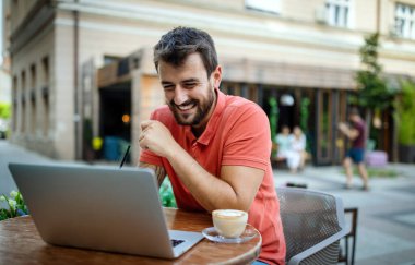 Laptoplu yakışıklı adam kafede boş zamanlarının tadını çıkarıyor.