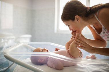 Güzel, sevgi dolu bir annenin portresi ilk maçlarını yatak odasında bebeğiyle oynuyor.