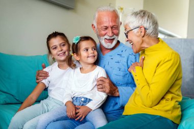 Mutlu büyükanne ve büyükbabalar evde torunlarıyla eğleniyor.