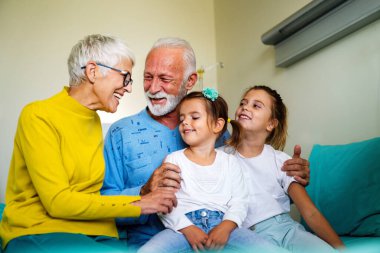 Mutlu büyükanne ve büyükbabalar evde torunlarıyla eğleniyor.