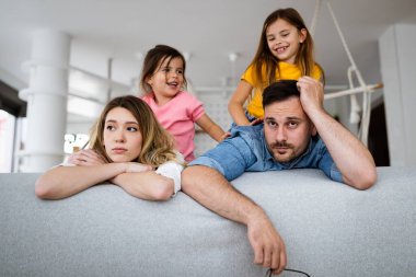 Yorgun anne ve baba, evde gürültücü çocuklar varken yorgun hissediyorlar.